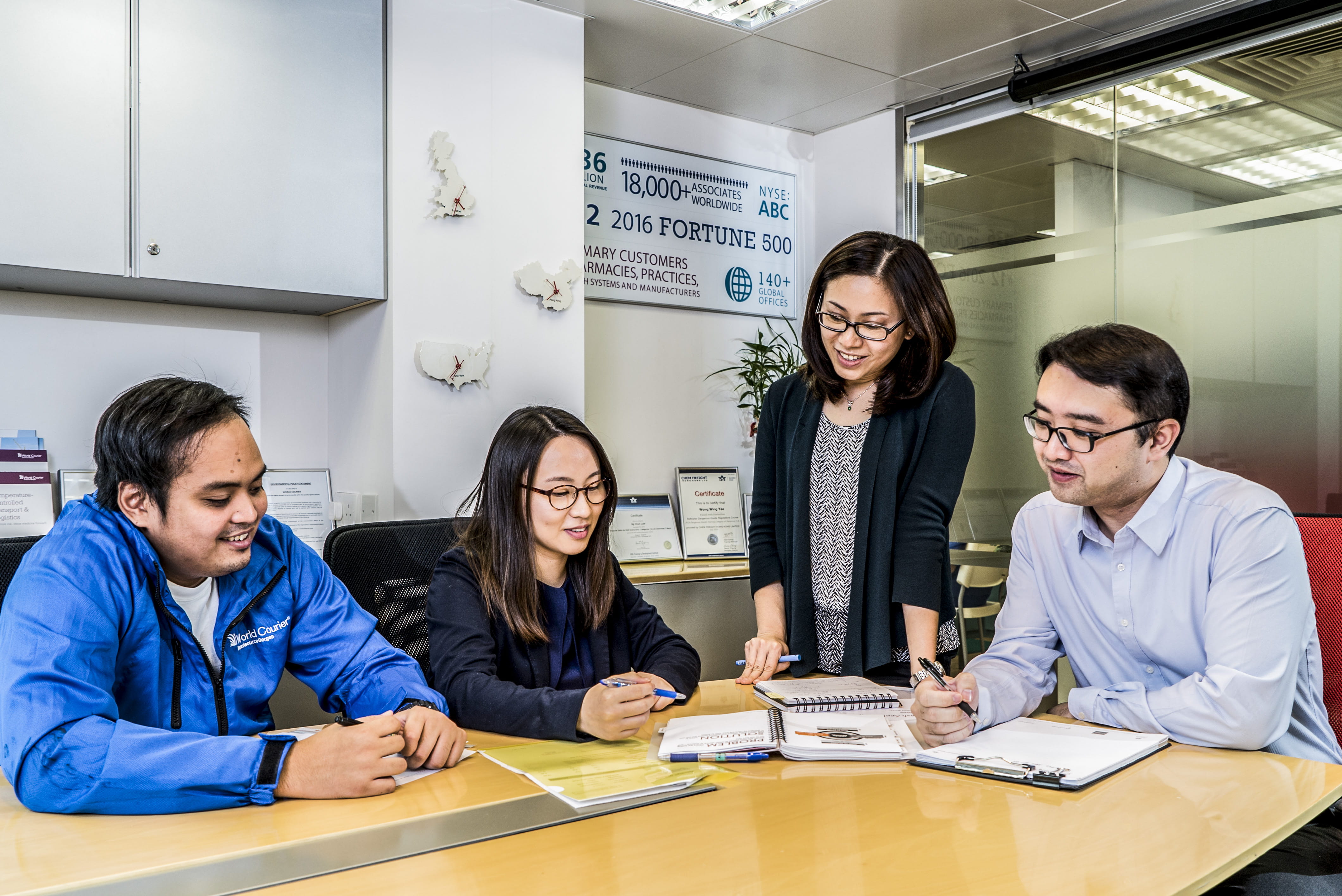 Four World Courier associates gather around a conference table in a meeting room.