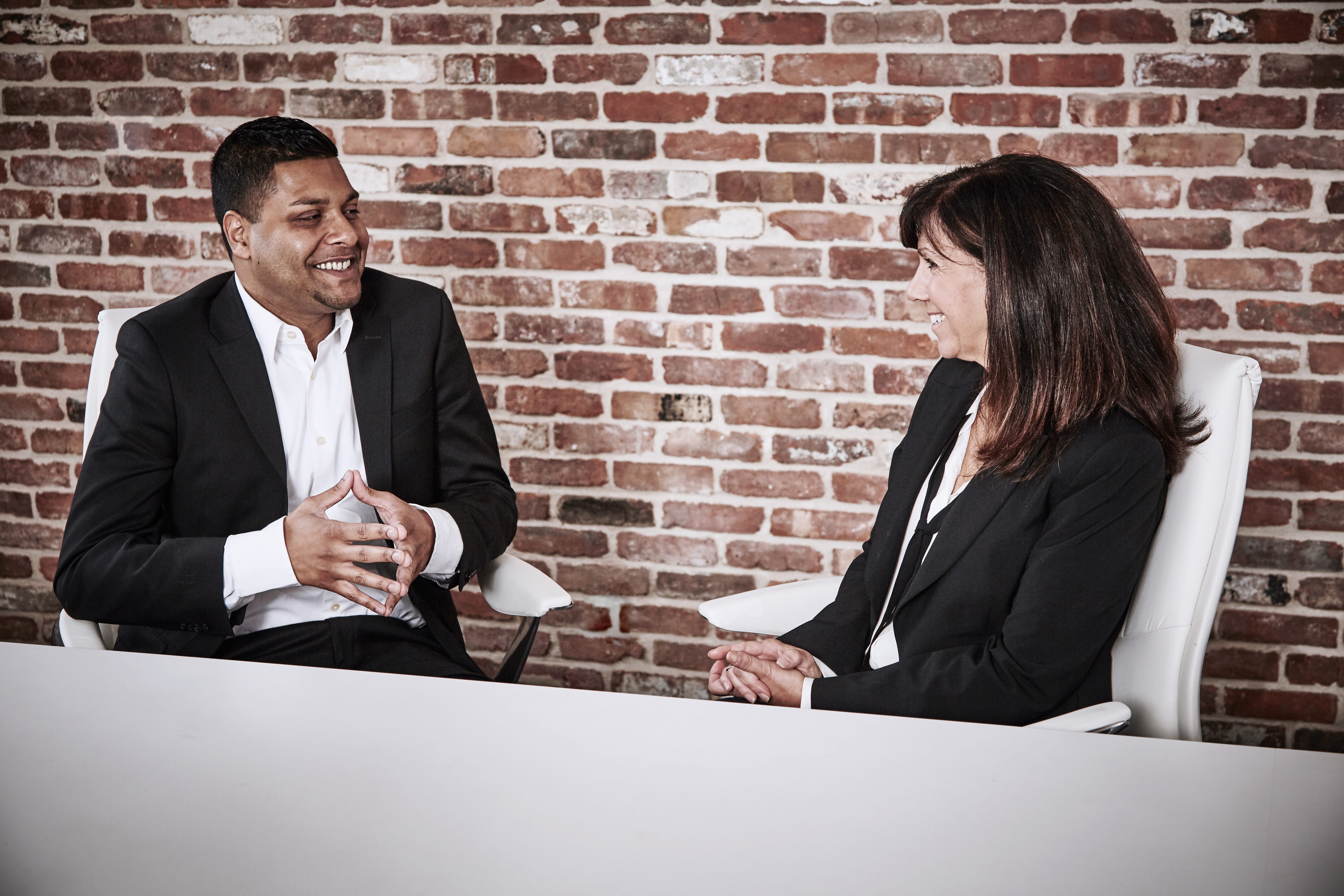 A man and a woman sit and talk at a conference table.
