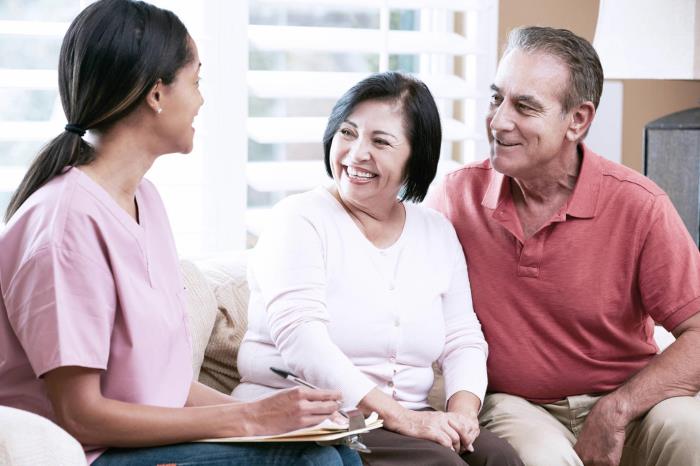 A visiting nurse talks to a man and a woman in their home.