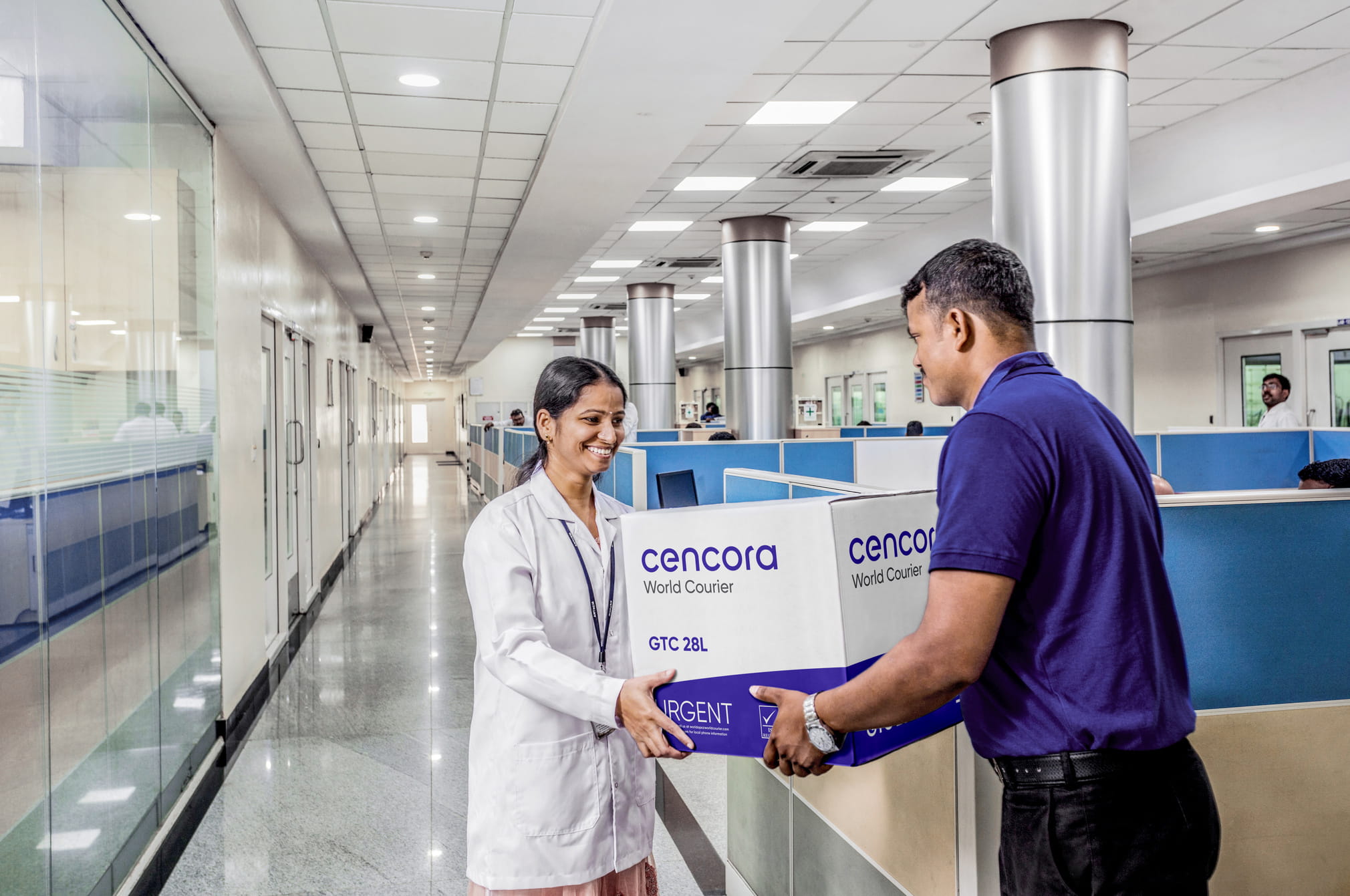 A World Courier associate delivers a shipment to a specialist in a lab coat inside a hospital