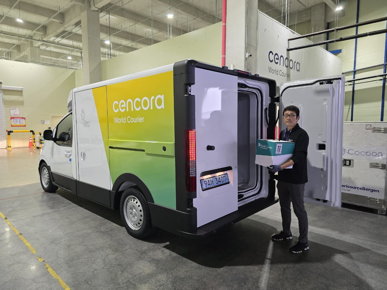 Picture of man holding box for delivery next to sustainable electric delivery van